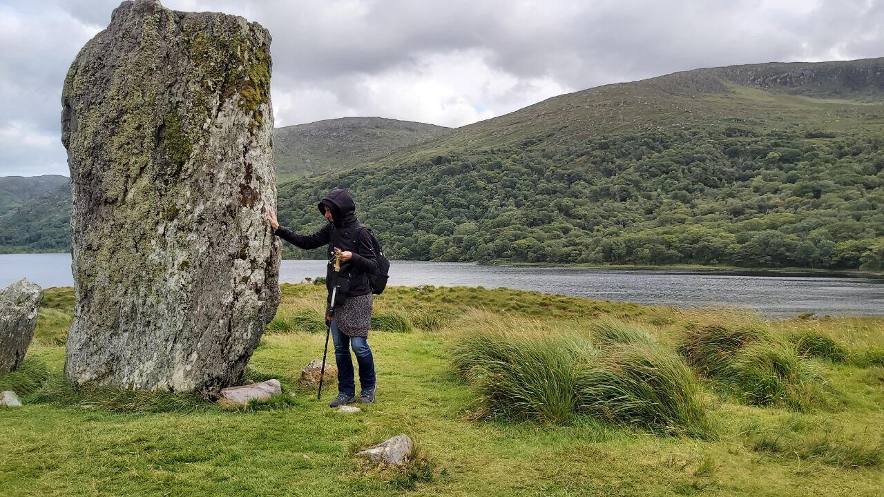 A solitary woman with an Irish standing stone, seeking answers to the question of how can I change myself