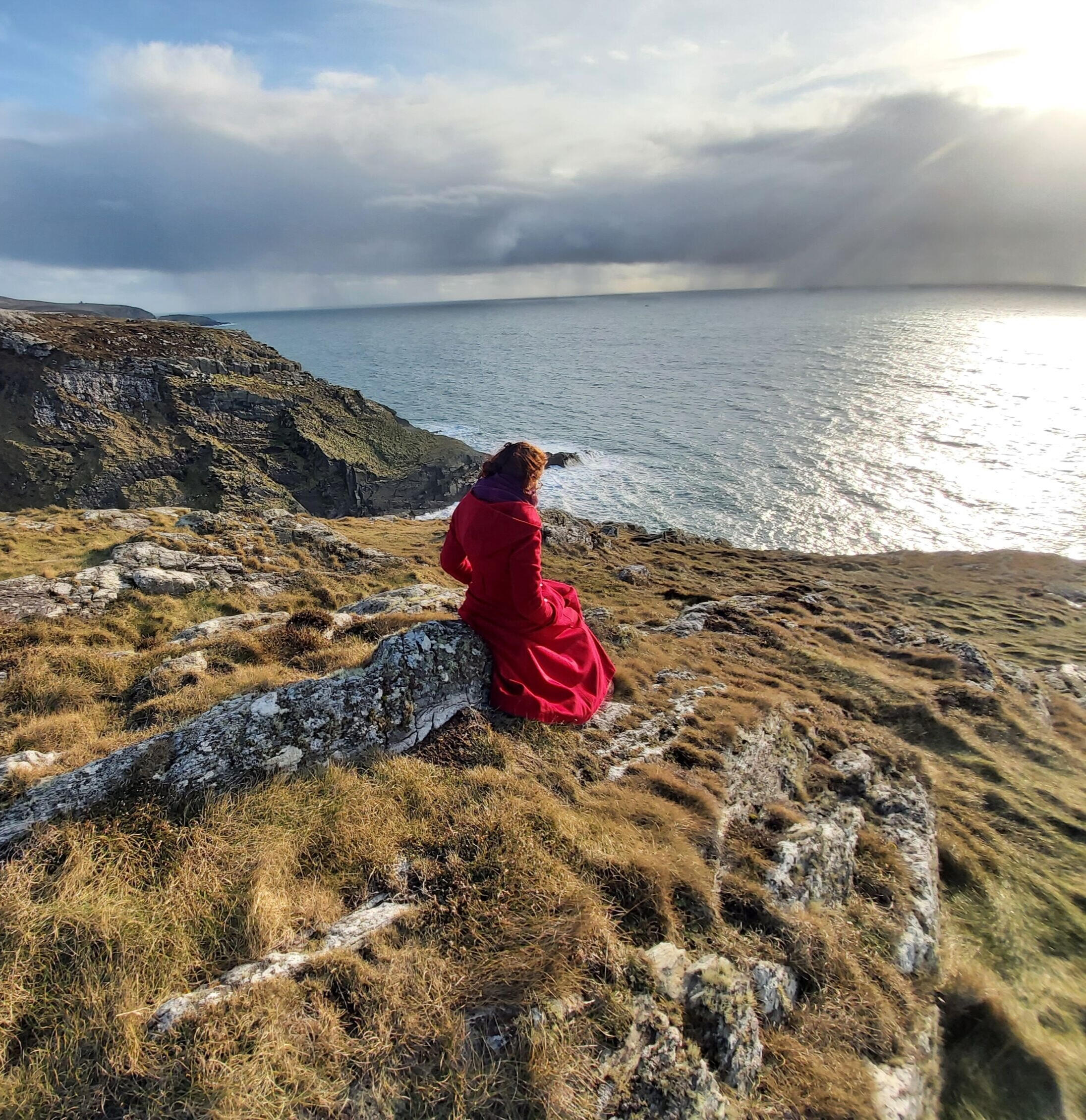 A woman overlooking the Atlantic Ocean as part of her transformative rites of passage for women